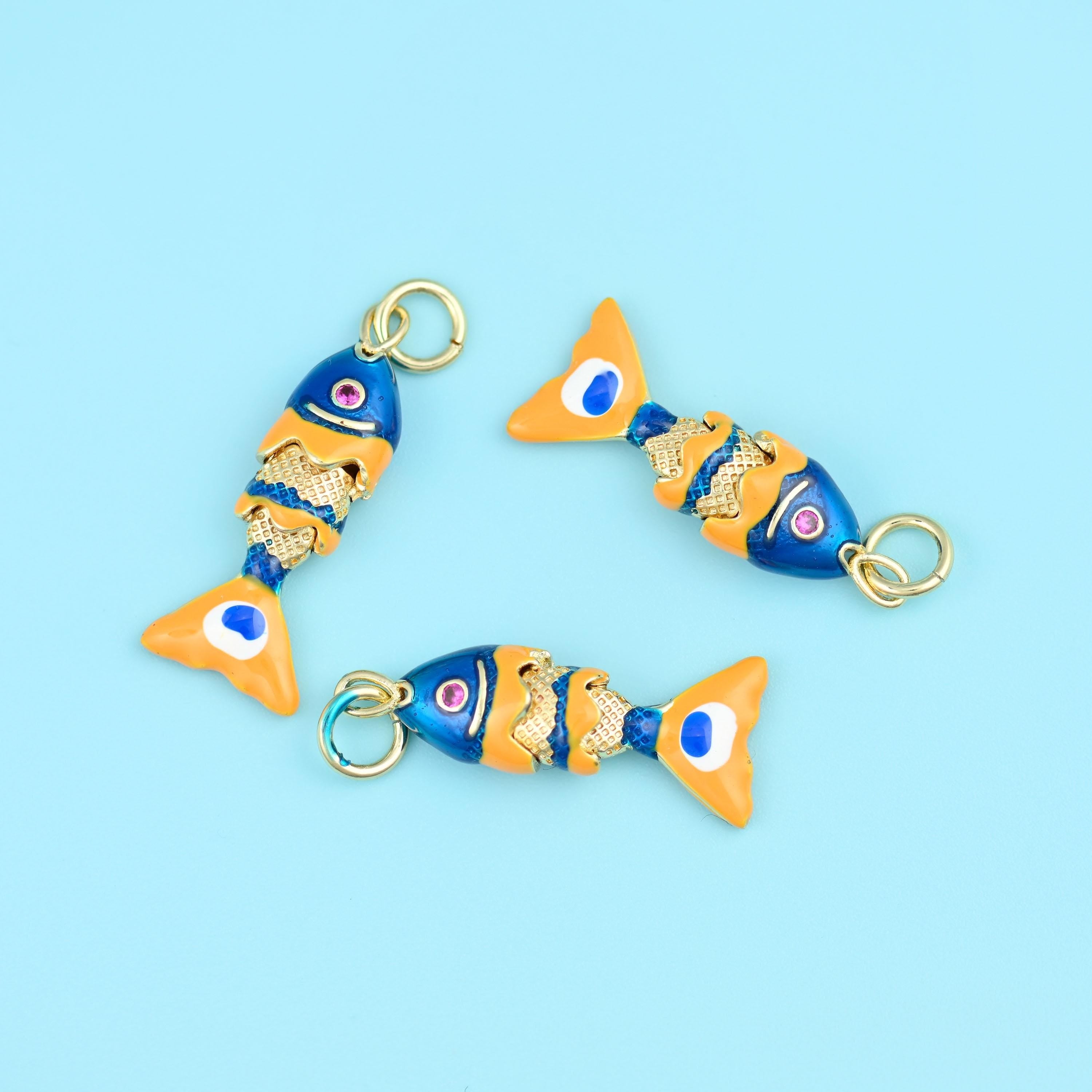 A slim fish built from jointed segments so the body flexes as it hangs: a deep cobalt enamelled head with a small ringed…