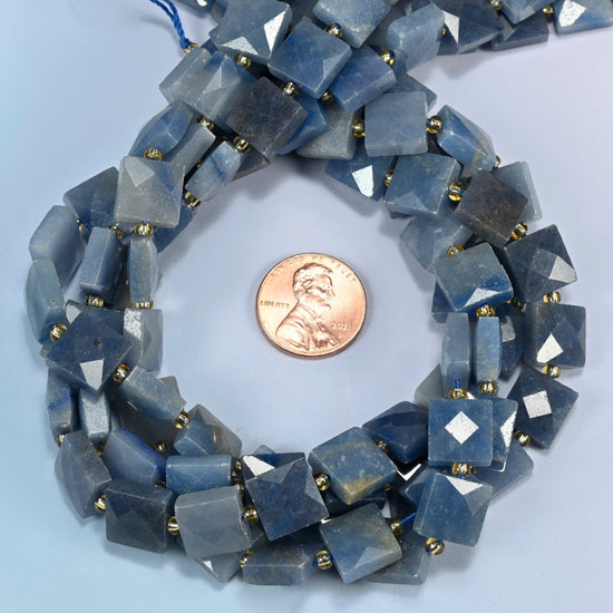 Natural blue aventurine faceted flat square beads 10x10mm coiled in a loop around a US penny for scale, close-up of the faceted flat square shape