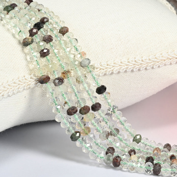 Green Phantom Quartz gemstone rondelle beads 4x6mm faceted, strand draped over a cream fabric cushion