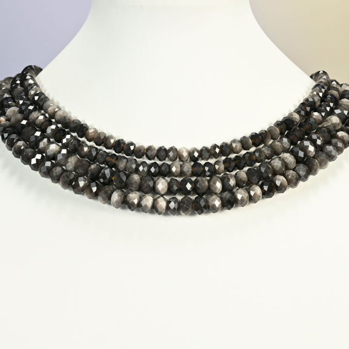 Silver obsidian beads shown on a white neck display, four faceted rondelle strands layered close to the neckline