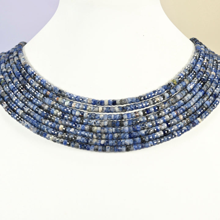 Sodalite faceted heishi disc strands arranged as a layered collar on a white display bust, blue and white beads across the neck