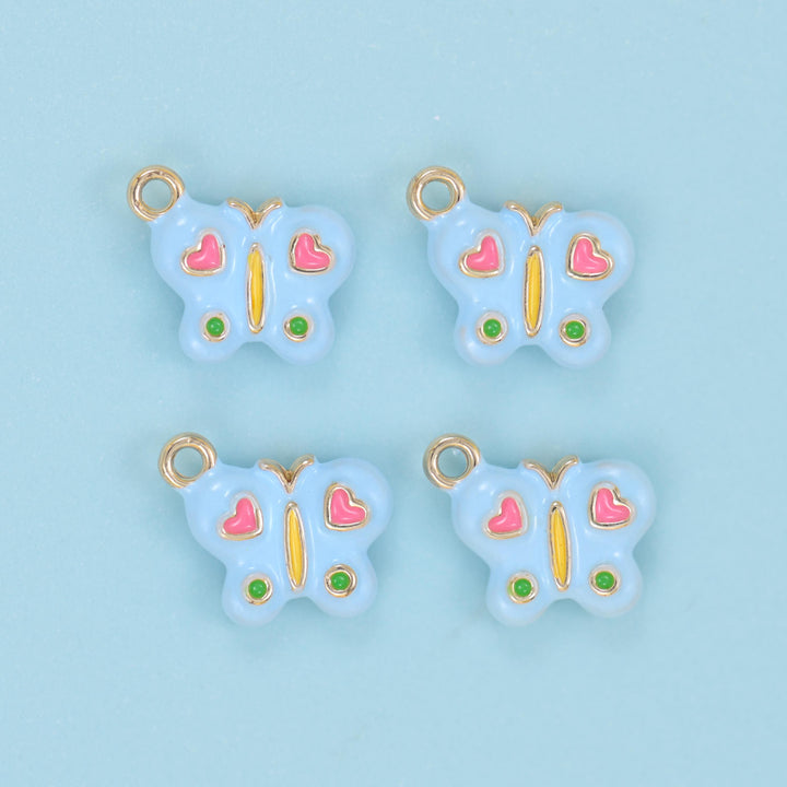 Enamel colorful butterfly charm in light blue, four pieces with pink enamel hearts on the upper wings, green dots on the lower wings and a slim gold body.