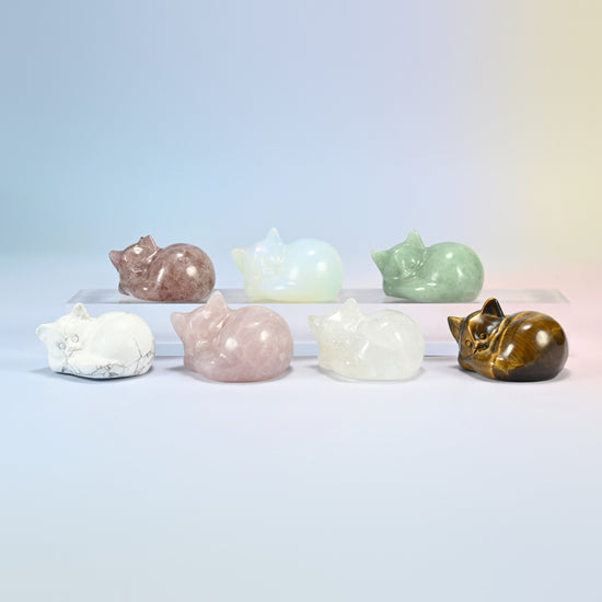 Seven 1.5 inch sleeping cat crystal carvings on a stand in natural stones and opalite (man-made glass)