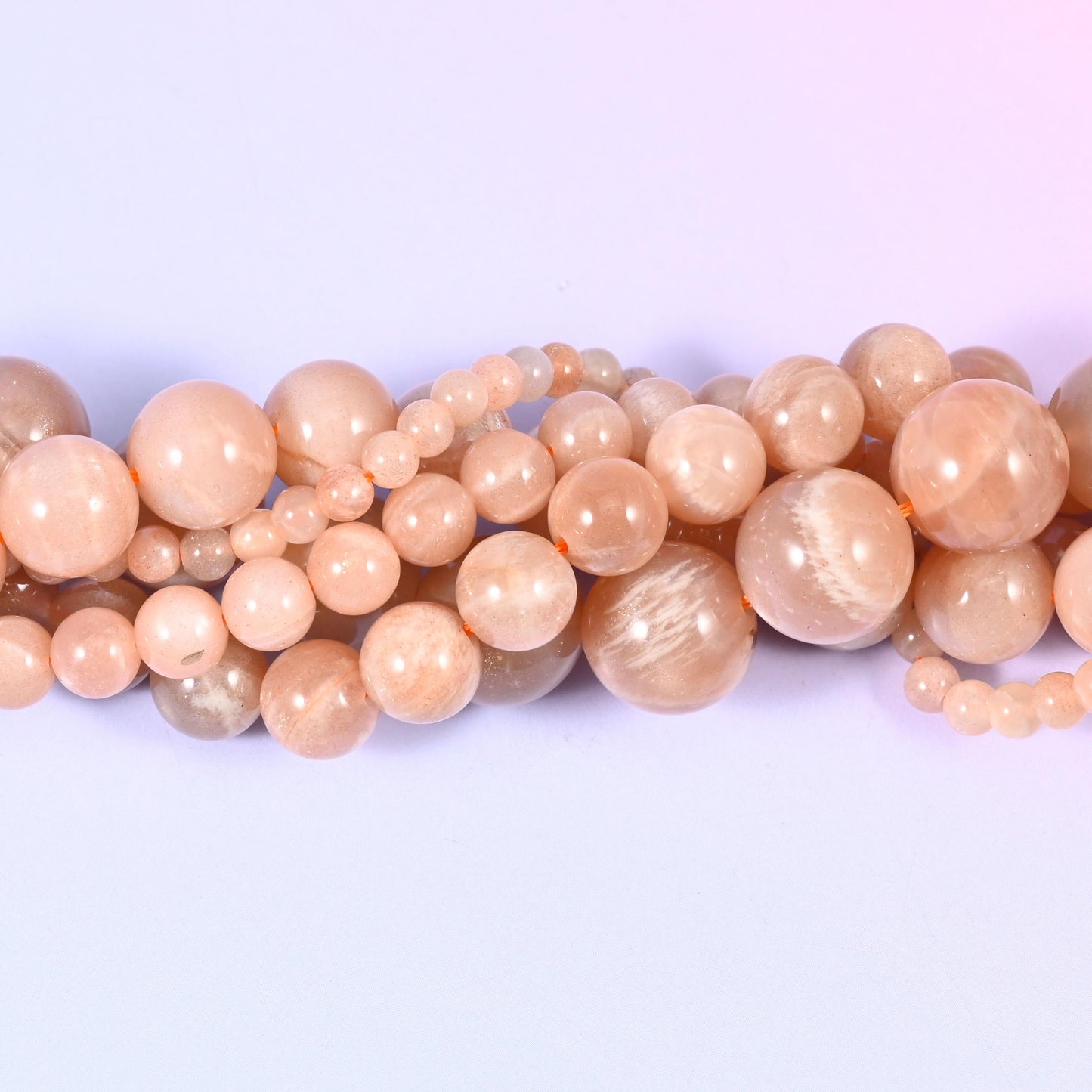 Peach Moonstone Smooth Round Beads, approximately 92 beads at 4mm and 32 at 12mm per strand.