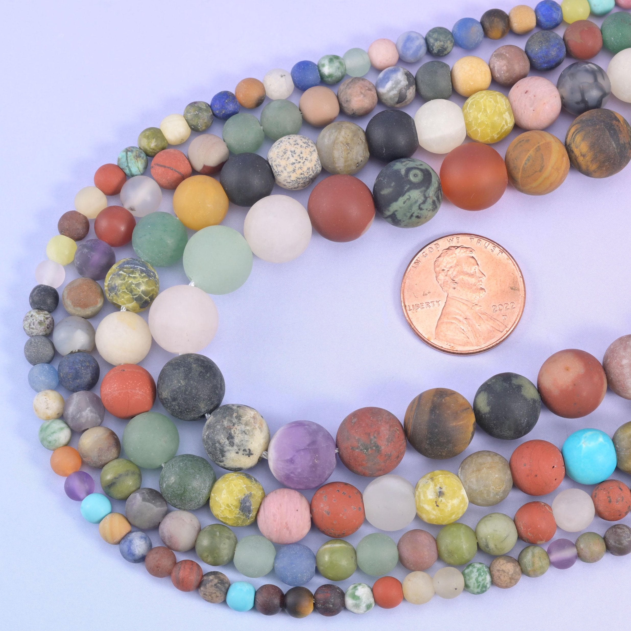 Assorted matte round beads looped around a US penny for size comparison