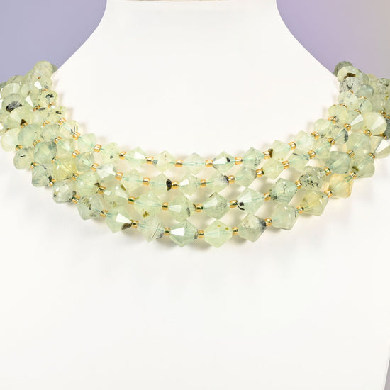 Strand of Green Prehnite faceted bicone beads, 8mm and 10mm, worn on a jewelry display bust, showing the necklace-length drape.