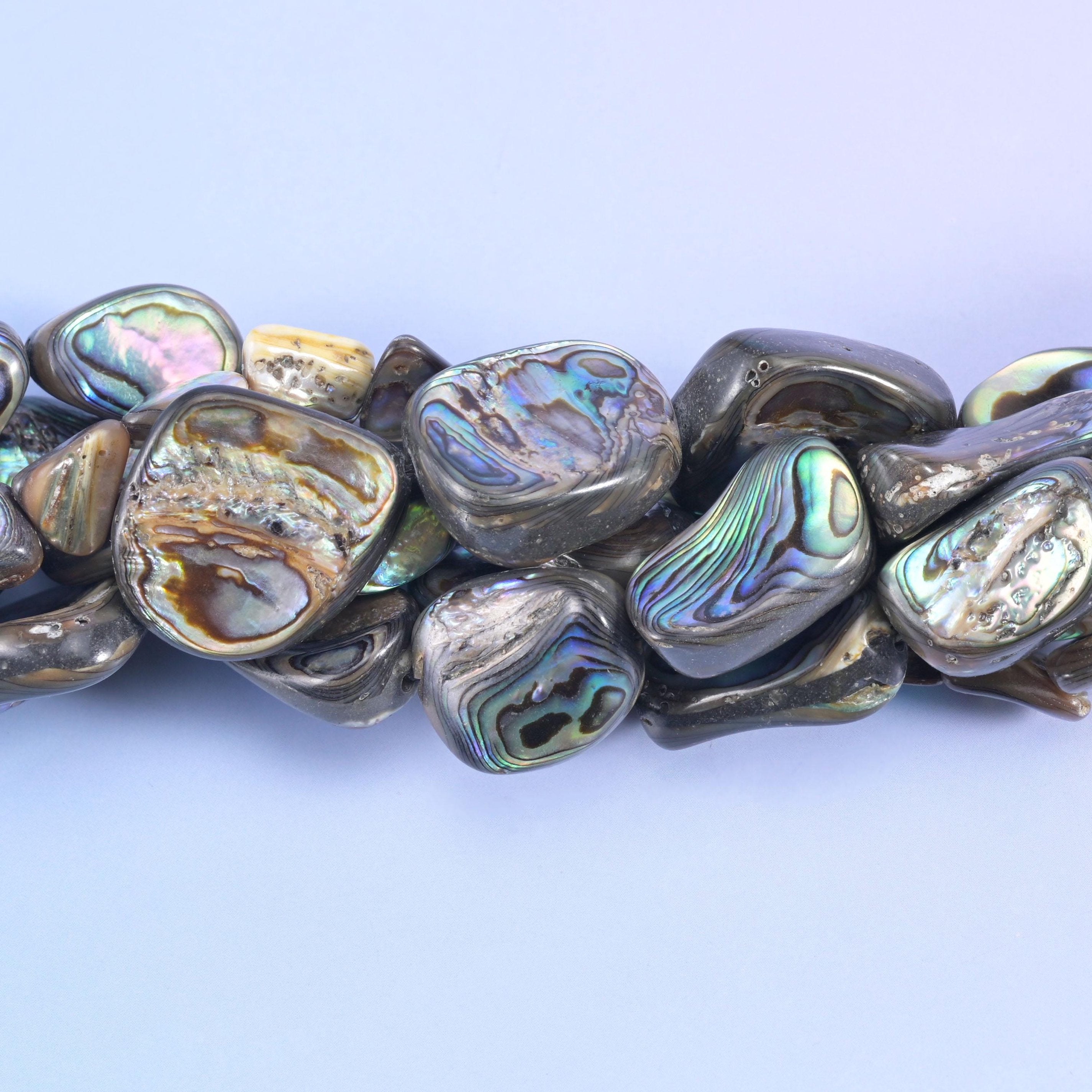 Silver-grey and bronze shell nuggets that flash blue, green and rose the moment they turn. Real abalone