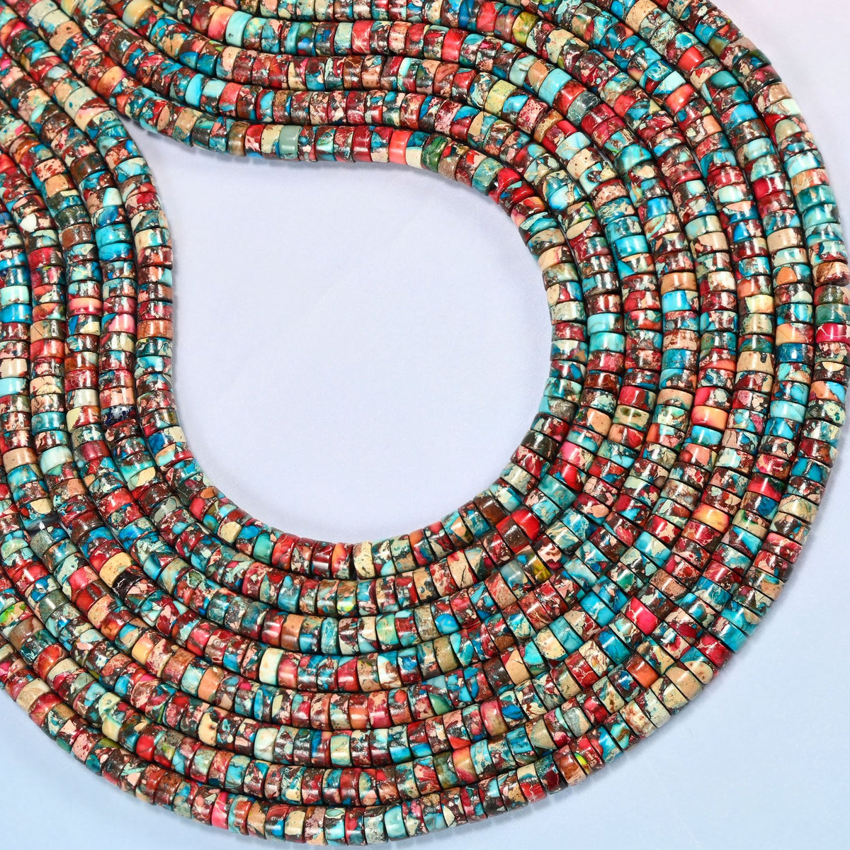 Dyed red blue sea sediment jasper heishi disc beads 2x4mm curved into an open loop, showing the turquoise and red mix across whole strands