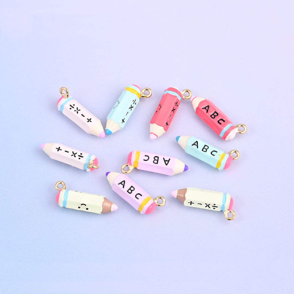 Ten pencil charms scattered, showing all five colors and both printed faces.