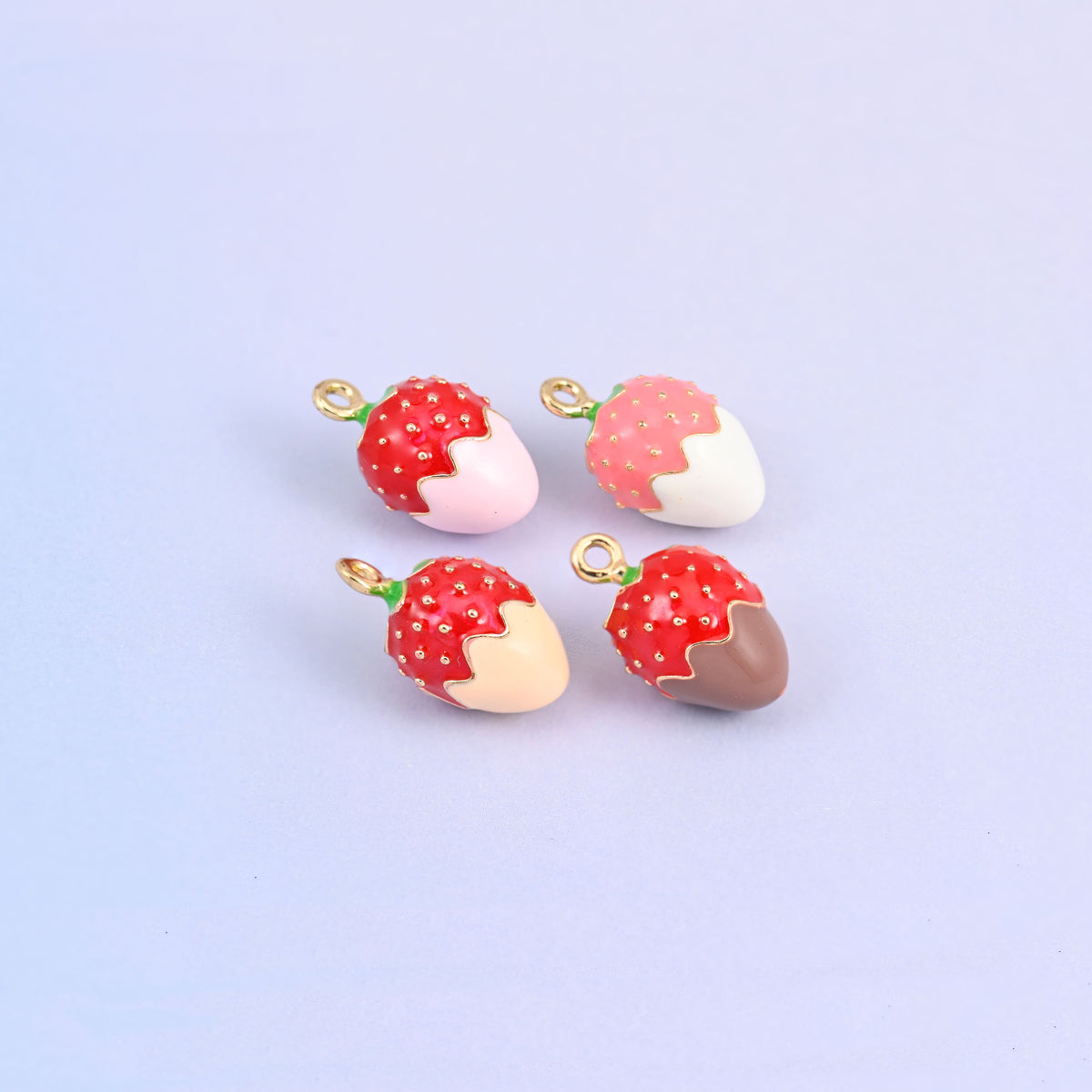 Four strawberry charms grouped, showing the white, light pink, light orange and brown dips side by side.