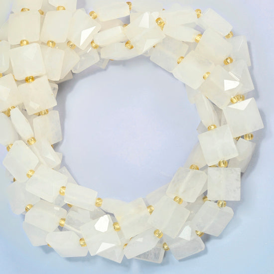 Clear quartz faceted flat square beads coiled into overlapping loops, whole strands of soft milky white stone