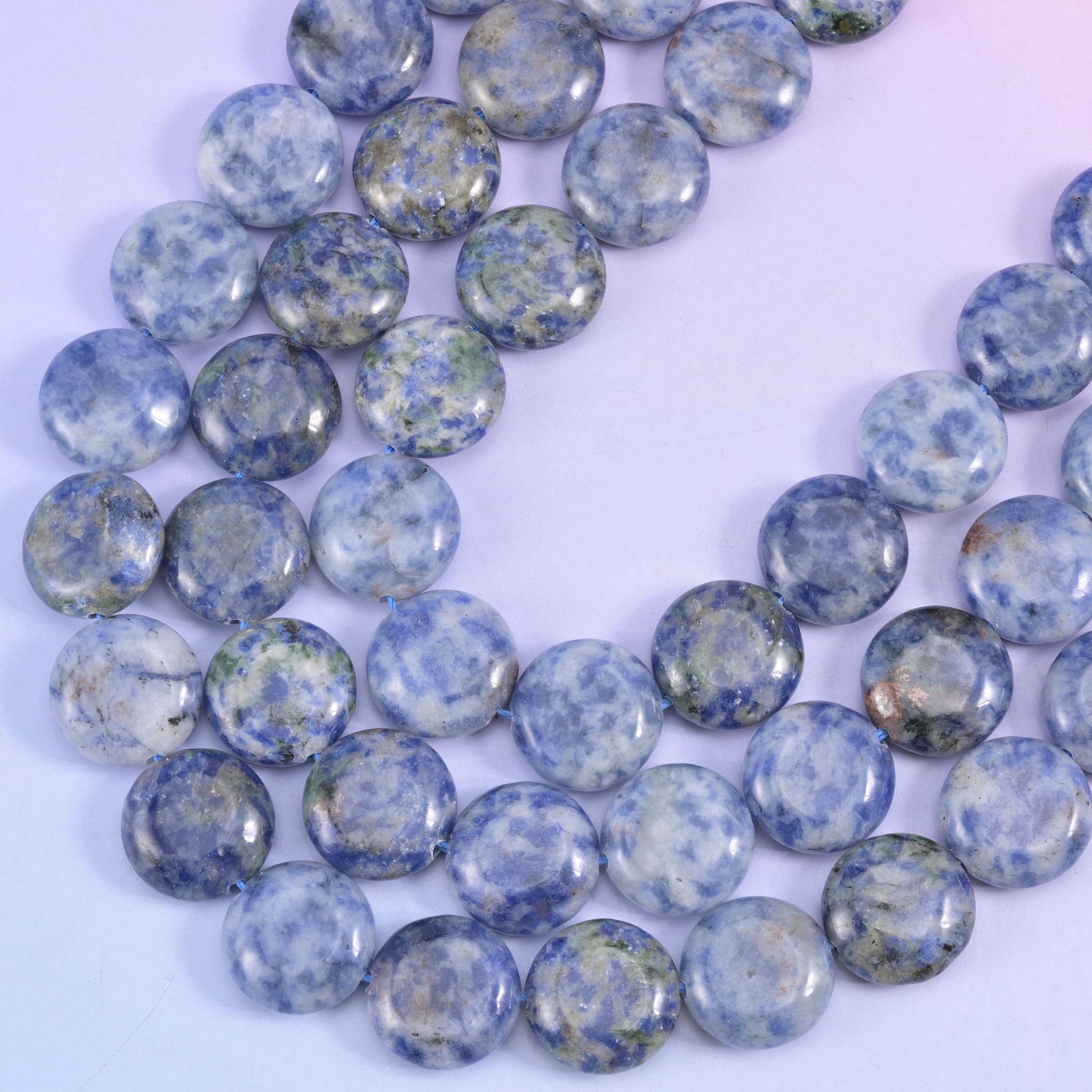 Side view of blue spot jasper discs revealing the flat coin profile and centre drill holes