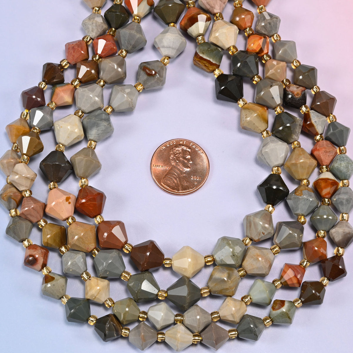 Close-up of American Picture Jasper faceted bicone beads, 8mm and 10mm, coiled into a circle, highlighting the multicolor scenic pattern of the stone.