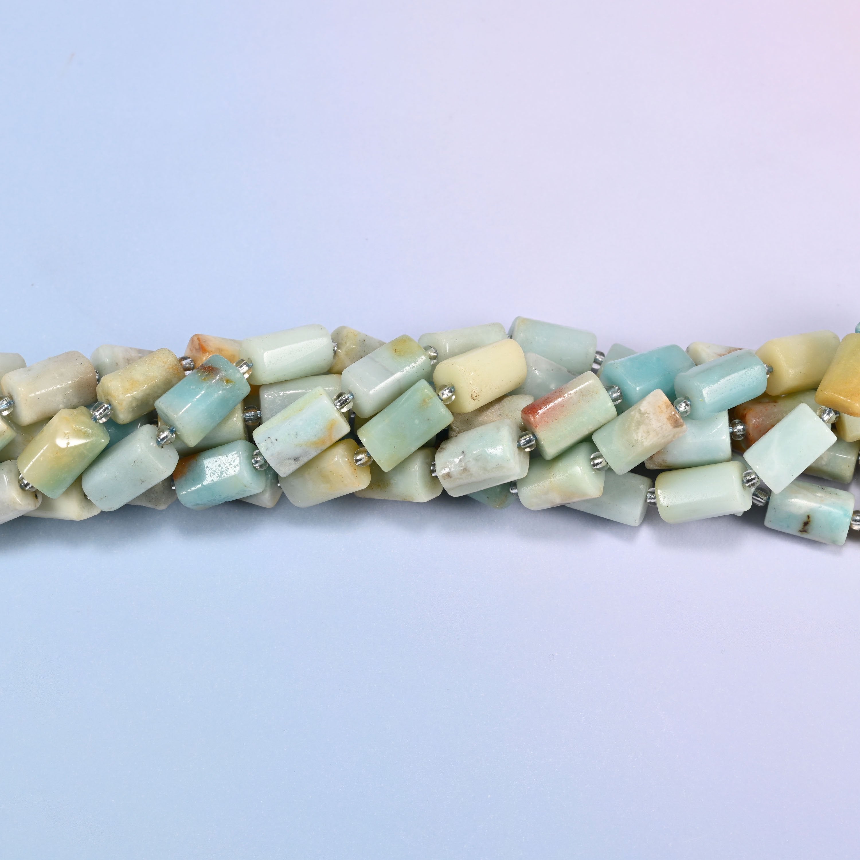 Close-up of Multi-Color Amazonite faceted tube beads showing the flat cut planes, polished surface and clear glass seed bead spacers
