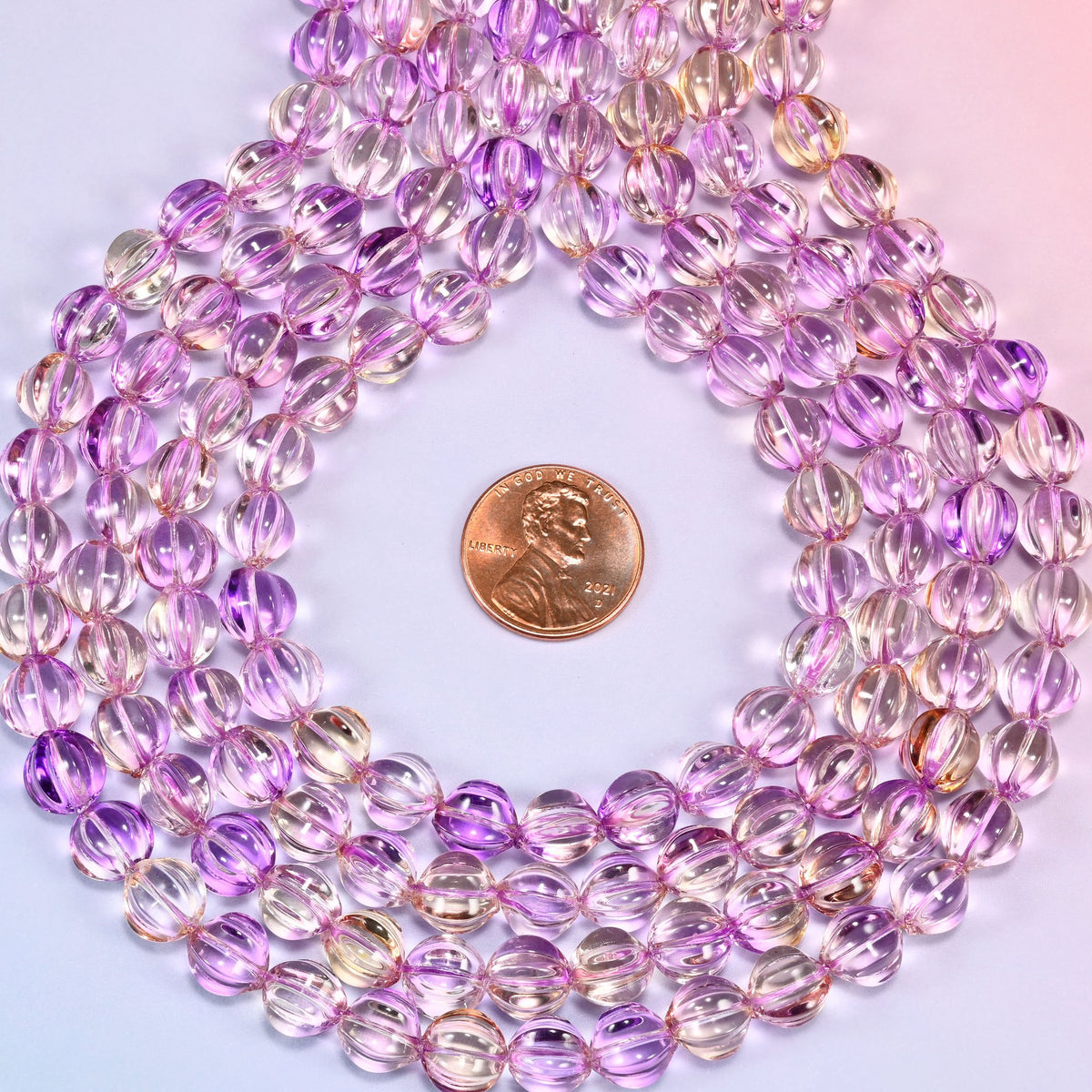 Clear purple gold pumpkin glass beads coiled flat into several concentric rings around an open center.