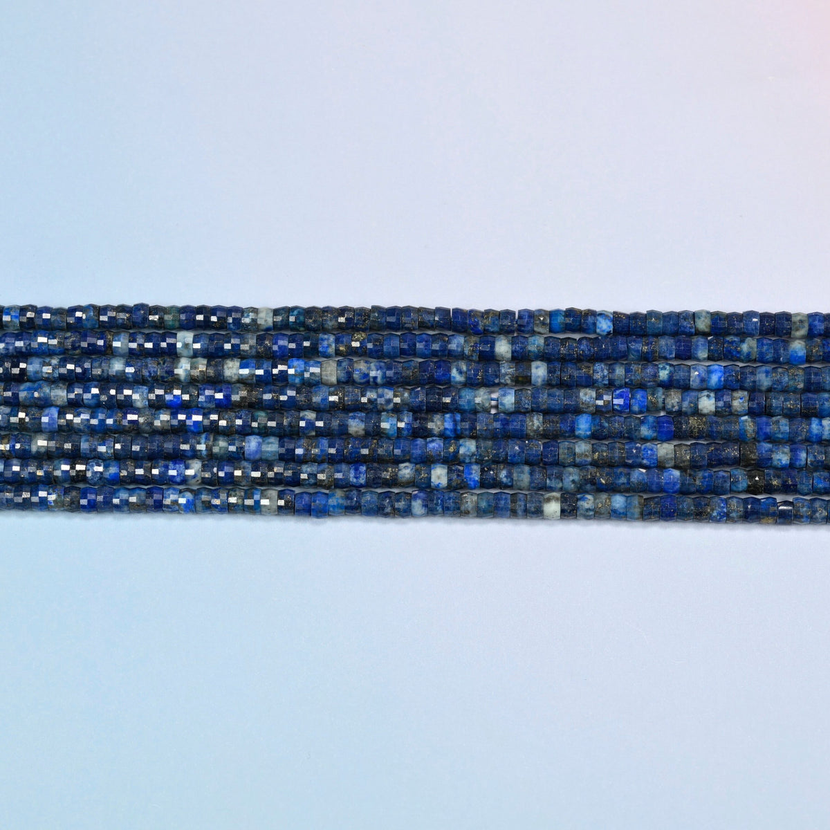 Several strands of dark blue lapis faceted heishi disc beads laid in straight rows