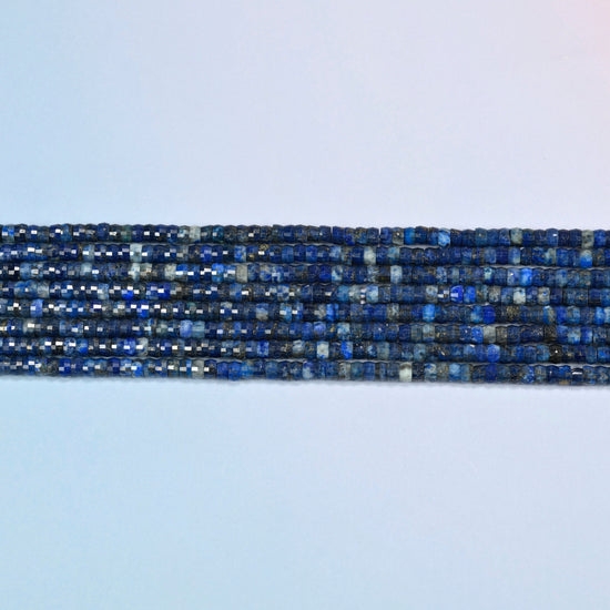 Several strands of dark blue lapis faceted heishi disc beads laid in straight rows