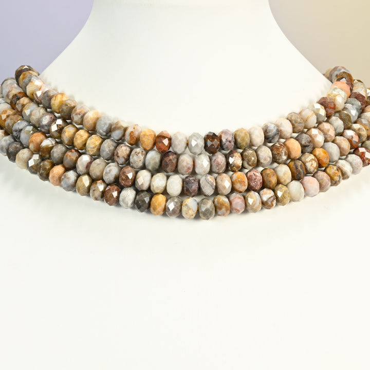 Gobi desert agate faceted rondelle strands arranged as a layered collar on a white display bust, desert tones across the neck