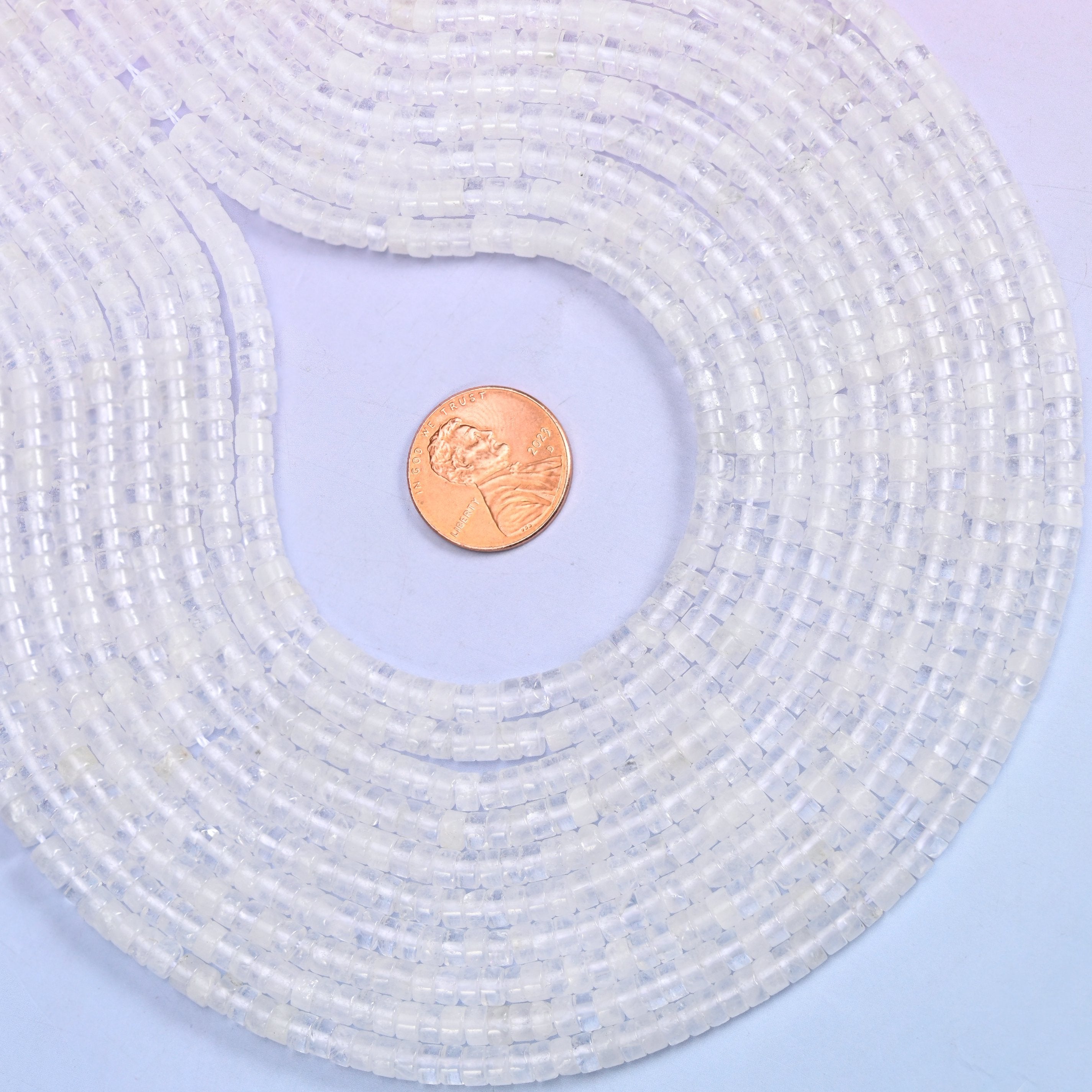 Translucent white through to almost water-clear, every disc polished until the flat face picks up the light. Roughly a hundred and eighty of them on a 15.5 inch strand.