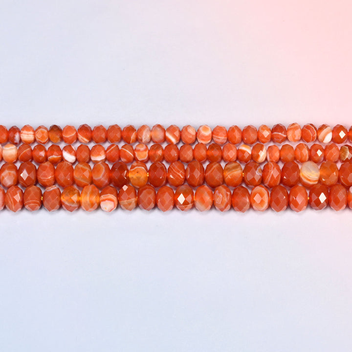 Dyed red strip agate faceted rondelle beads laid out in straight horizontal rows on a plain background, showing the even rondelle shape and bead size