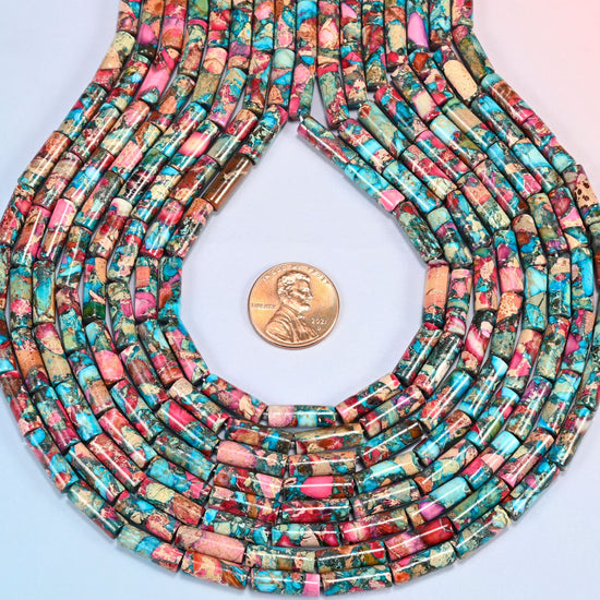 Dyed sea sediment jasper tube bead strands formed into a teardrop loop around a US penny for scale