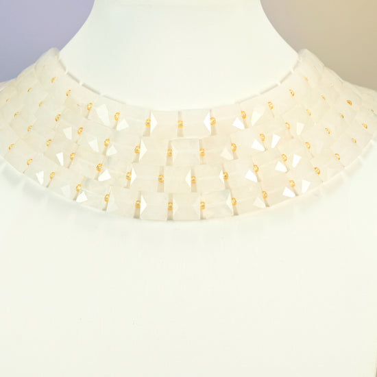 Clear quartz faceted flat square strands arranged as a layered collar on a white display bust, milky white beads across the neck