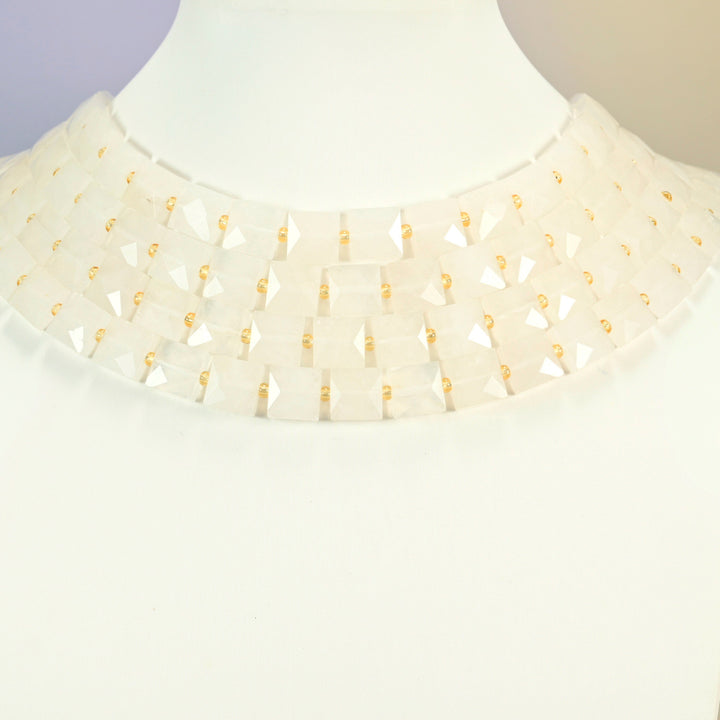 Clear quartz faceted flat square strands arranged as a layered collar on a white display bust, milky white beads across the neck