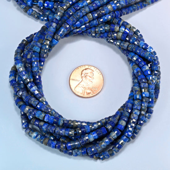 Lapis faceted heishi disc beads 2x4mm coiled in a loop around a US penny for scale, close-up of the faceted disc shape