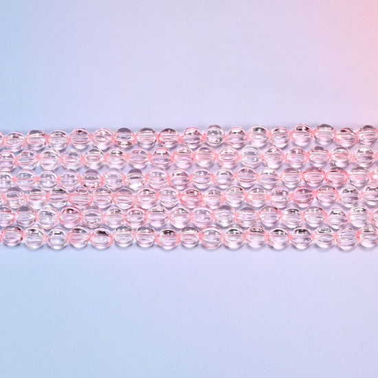 Close-up of 8mm clear pink pumpkin glass beads in four horizontal rows, showing the carved melon ribs.