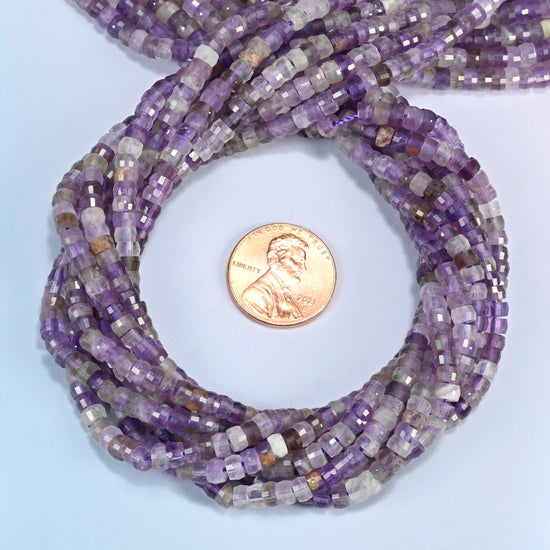 Amethyst faceted heishi disc beads 2x4mm coiled in a loop around a US penny for scale, close-up of the faceted disc shape