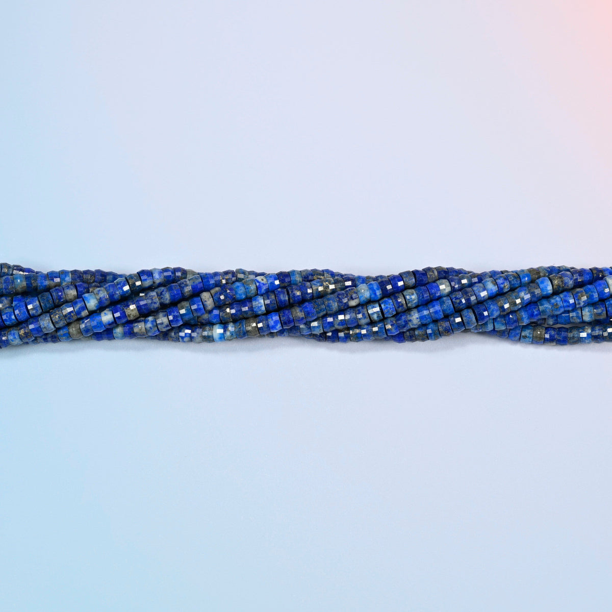 Strands of lapis faceted heishi disc beads twisted together in a horizontal row