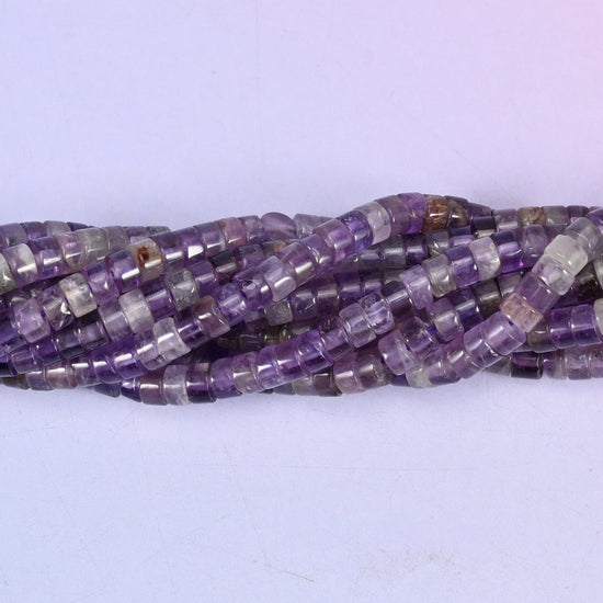 Purple running from pale lilac at one bead to deep violet at the next, translucent enough to glow when light sits behind it, cut into slim polished discs.