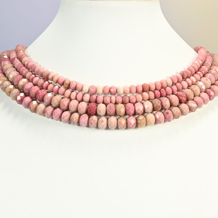 Pink rhodonite beads shown on a white neck display, the faceted rondelle strands sitting close to the neckline