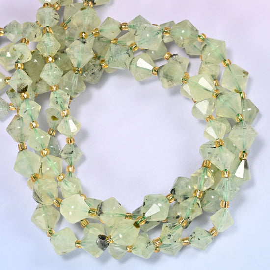 Green Prehnite faceted bicone beads, 8mm and 10mm, coiled into a tight circle on a light lavender background.