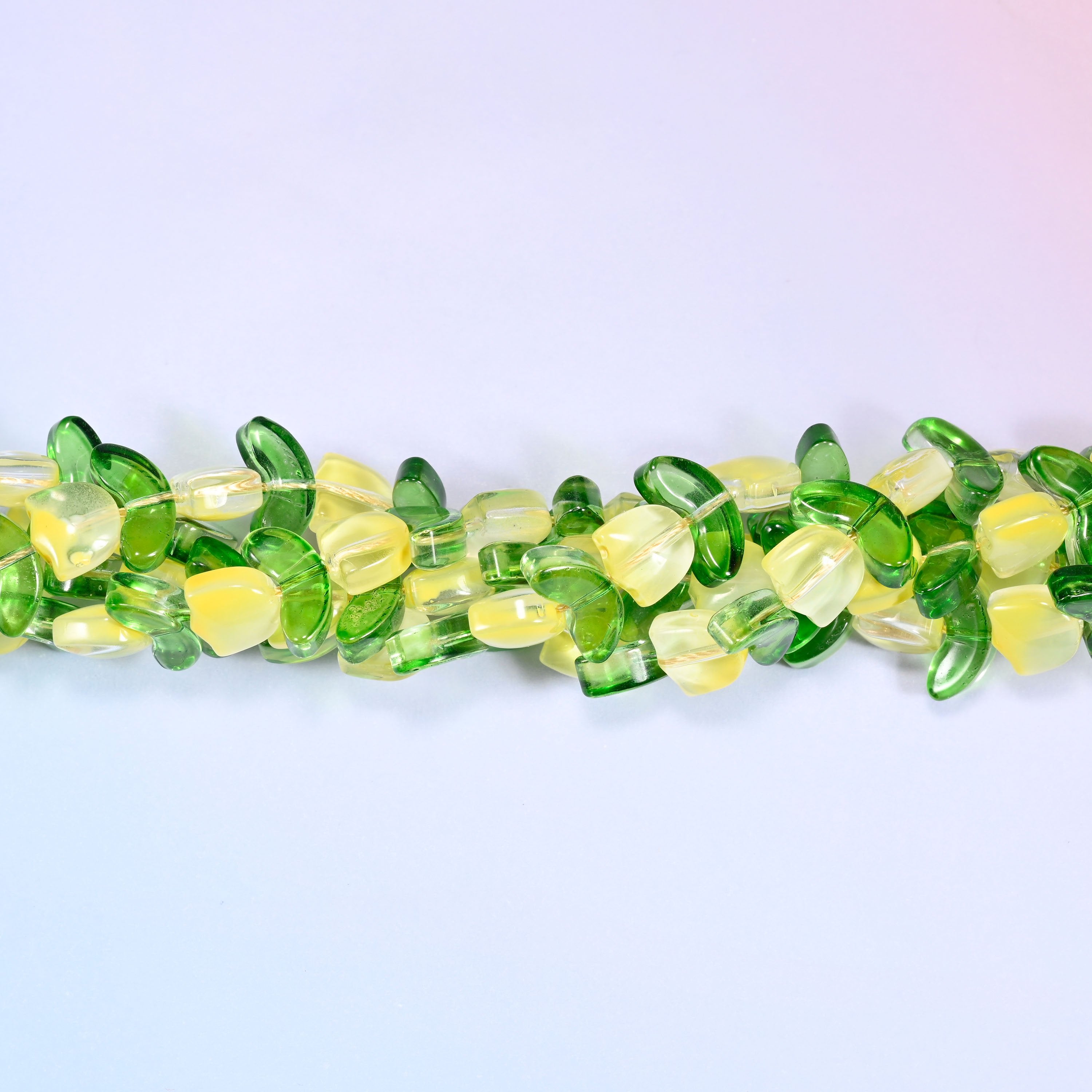 Close-up of a circular coil of yellow tulip and green leaf glass beads, showing the dense flower and leaf pattern.