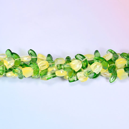Close-up of a circular coil of yellow tulip and green leaf glass beads, showing the dense flower and leaf pattern.