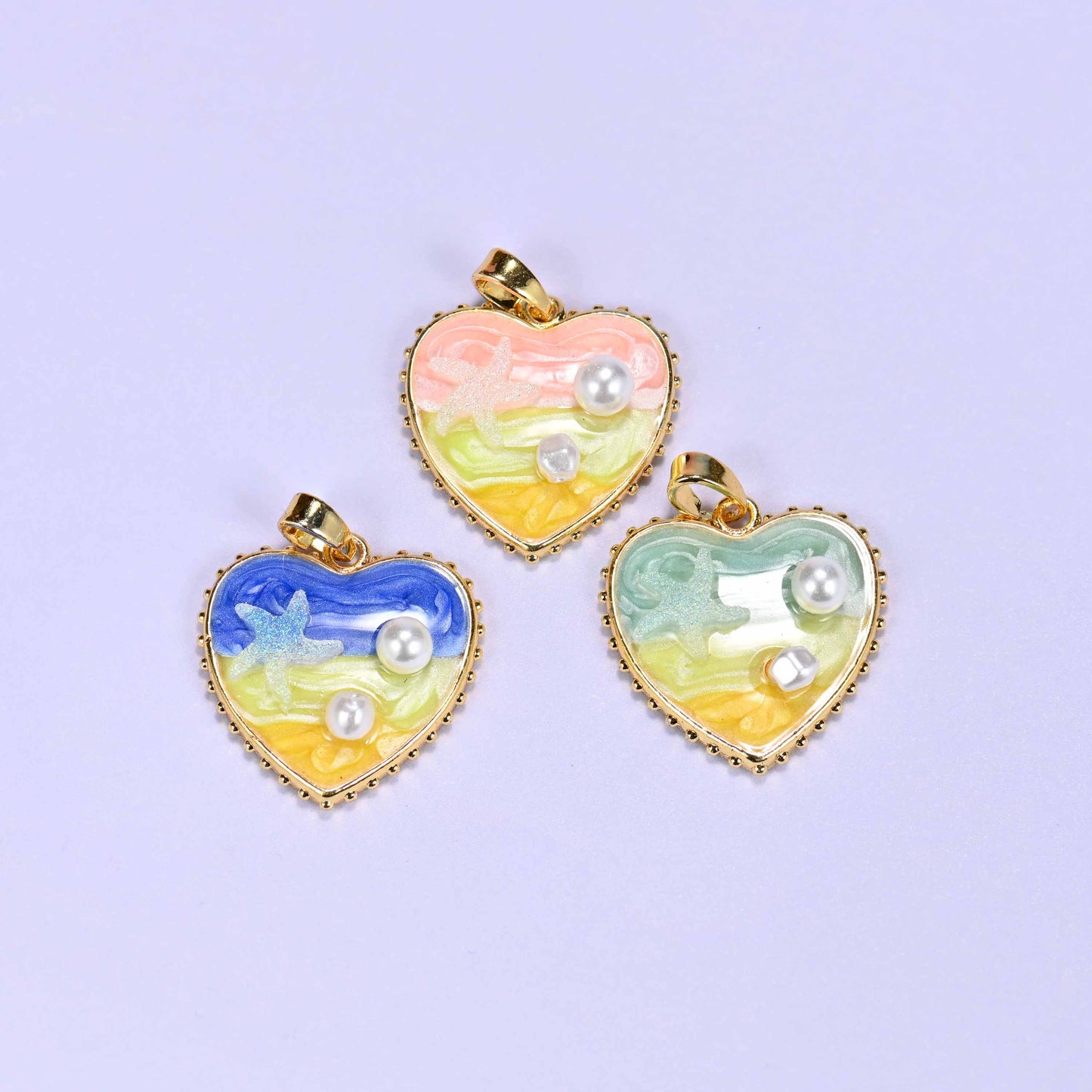 Enamel Heart Pendants colour options together, pink at the top with the blue and green hearts below, all with gold beaded edging and a hinged bail.