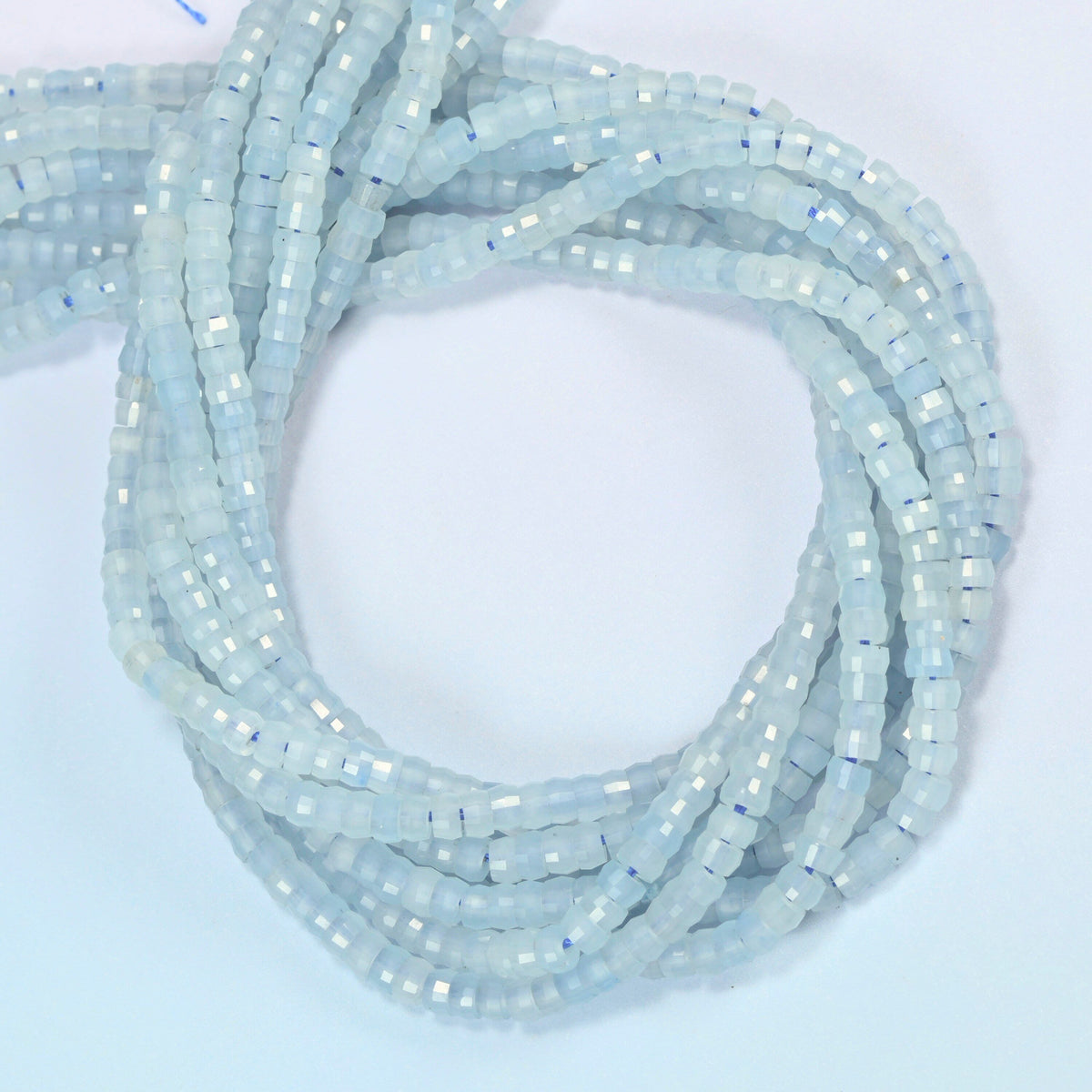Aquamarine chalcedony faceted heishi disc beads coiled into overlapping loops, whole strands of light blue stone