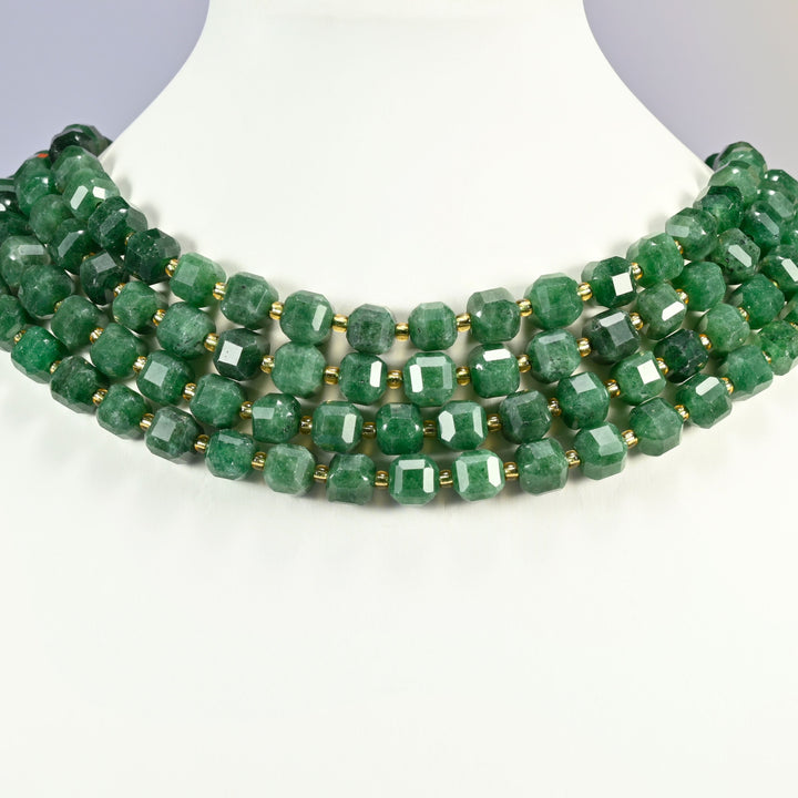 Natural green jade faceted cube strands layered as a collar on a white display bust, mottled green cubes with bright flashes on the cut faces