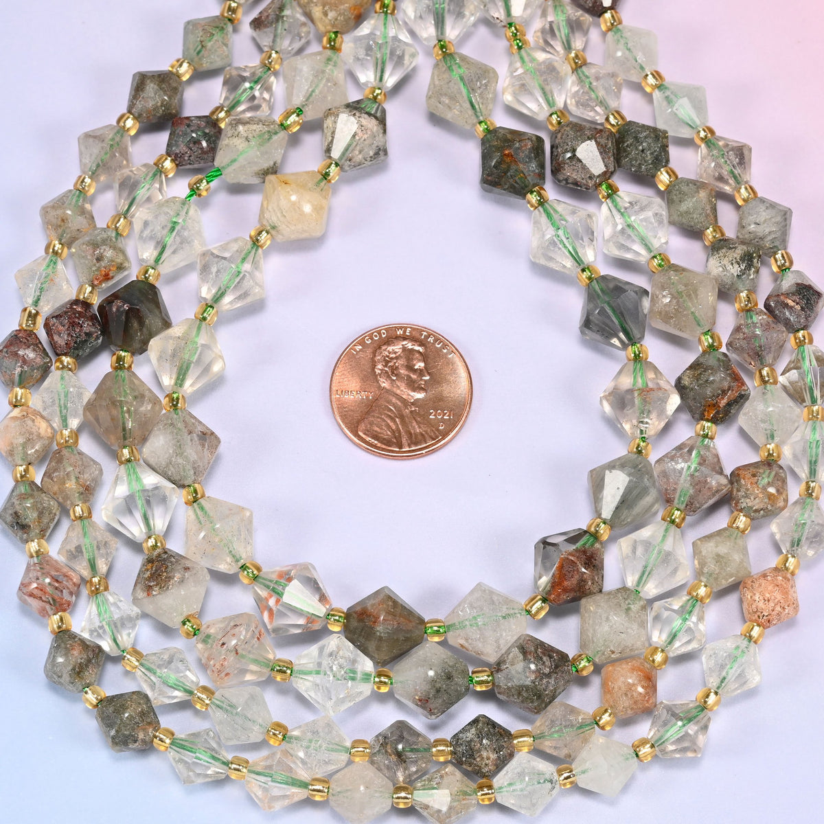 Close-up of Green Phantom Quartz faceted bicone beads, 8mm and 10mm, coiled into a circle, showing the green phantom inclusions and translucent facets.