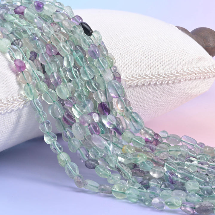 Mint green and purple fluorite nugget strands spilling over a white cushion