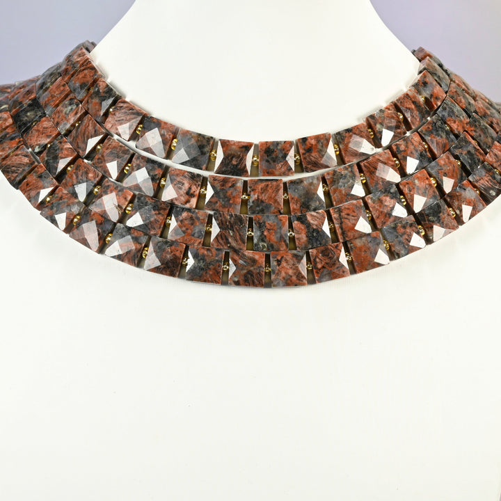 Natural red sesame jasper faceted flat square strands arranged as a layered collar on a white display bust, brick red beads across the neck