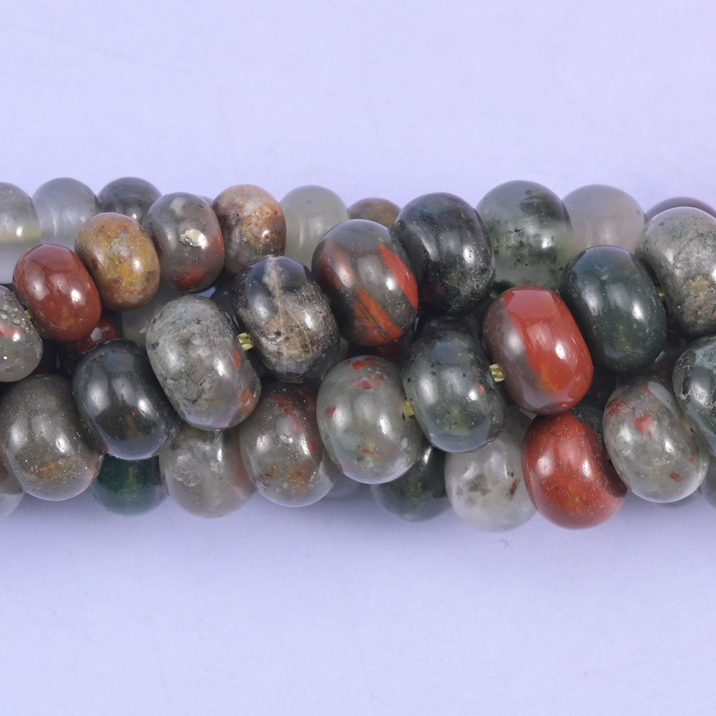 Deep forest and grey-green stone splashed with brick red and rust, some beads clouded pale grey, all polished smooth into flattened rondelles that stack tight against each other with no gaps.