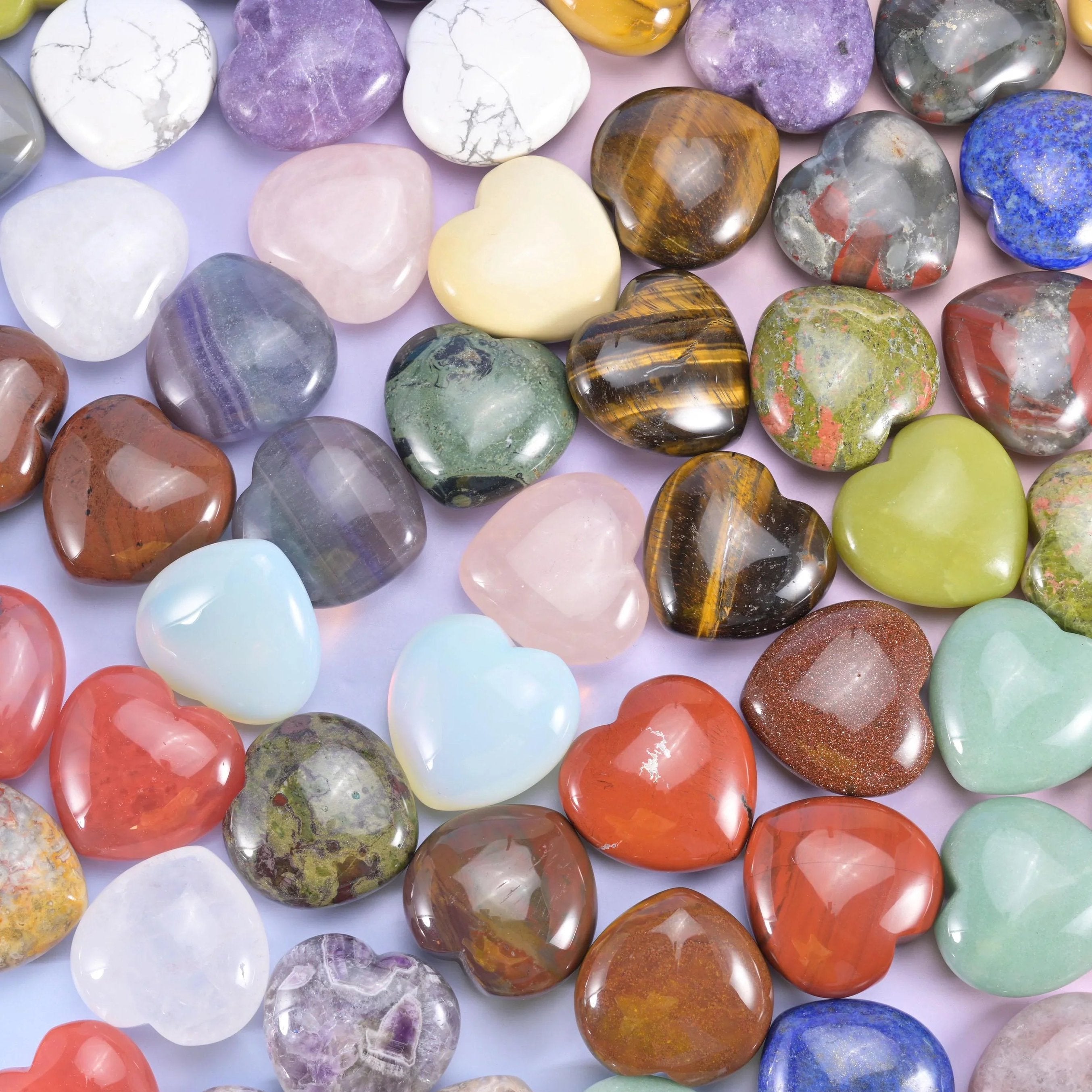 Dozens of 40mm polished stone hearts heaped together, from tiger eye and lapis to rose quartz and white howlite