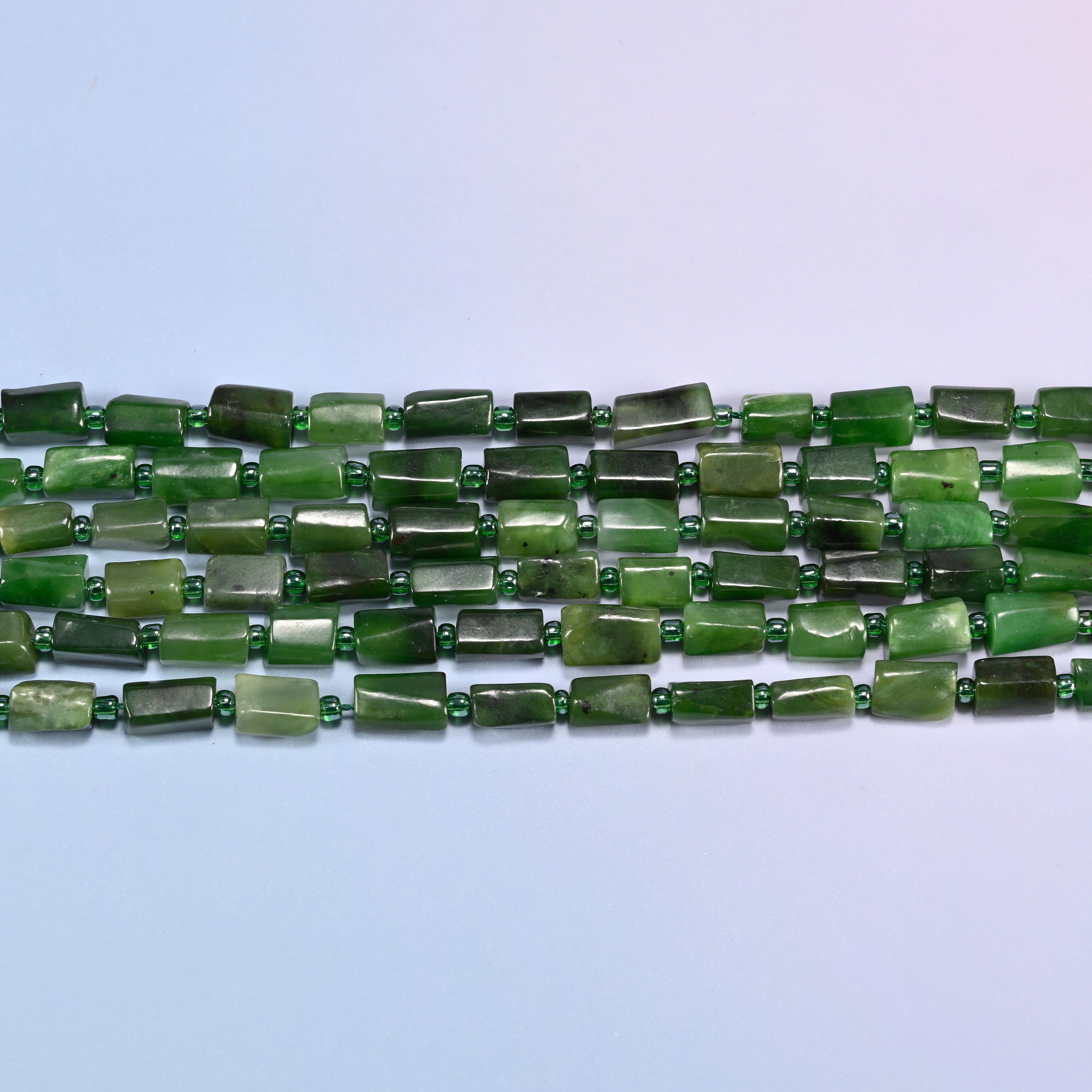 Side view of Canadian Green Jade faceted tube beads laid straight in two rows, showing the flat polished planes and short irregular lengths
