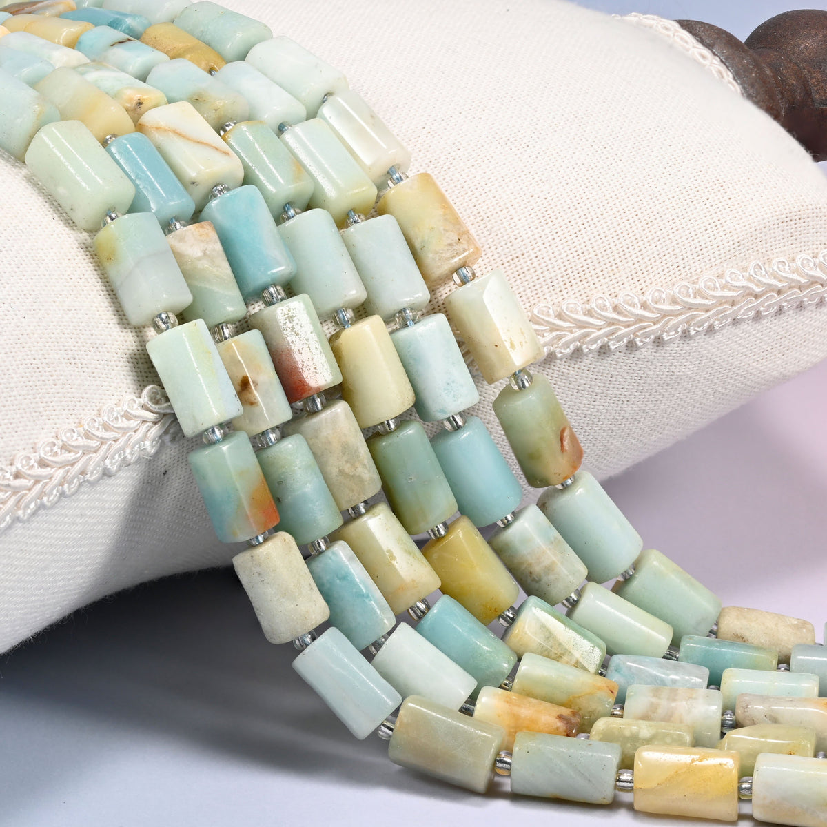 Multi-Color Amazonite faceted tube beads draped in rows, light blue and green tubes mixed with cream, white and yellow, spaced with small clear glass seed beads
