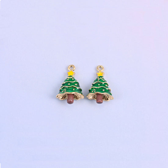 Two christmas tree charms side by side, green enamel over 18K gold plated brass with yellow star toppers and brown trunks.
