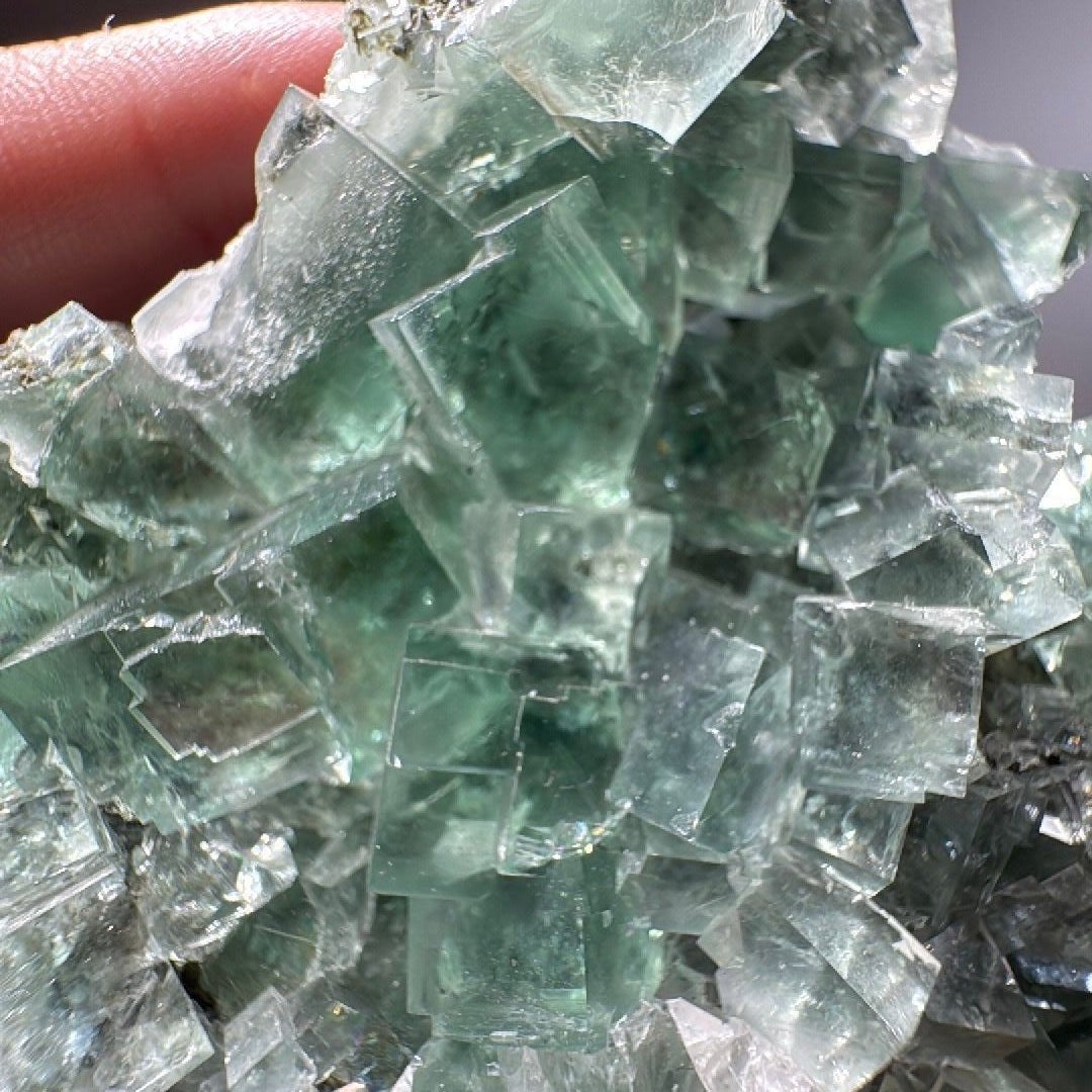 Close view of transparent green Fluorite cubes stacked across the cluster