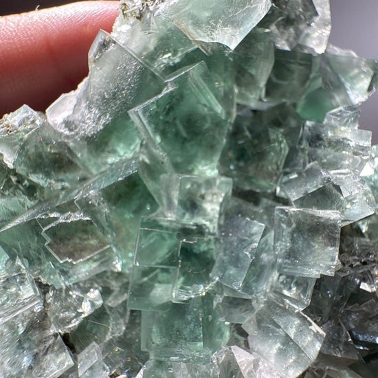Close view of transparent green Fluorite cubes stacked across the cluster
