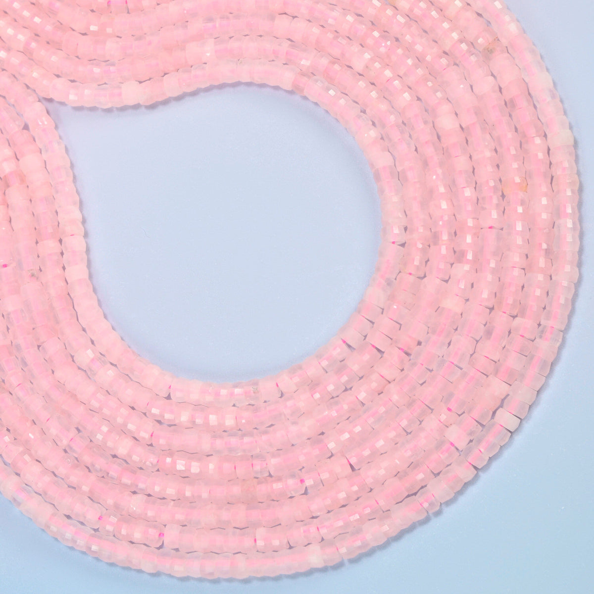 Rose quartz faceted heishi disc beads curved into an open loop, soft pink beads